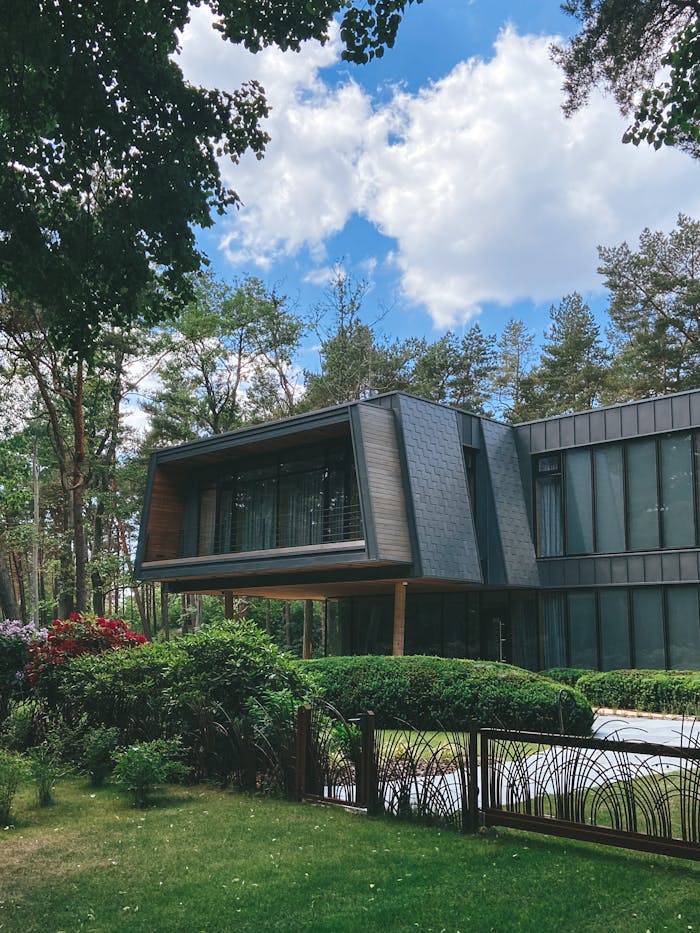 Contemporary luxury house exterior surrounded by lush garden on a sunny day.