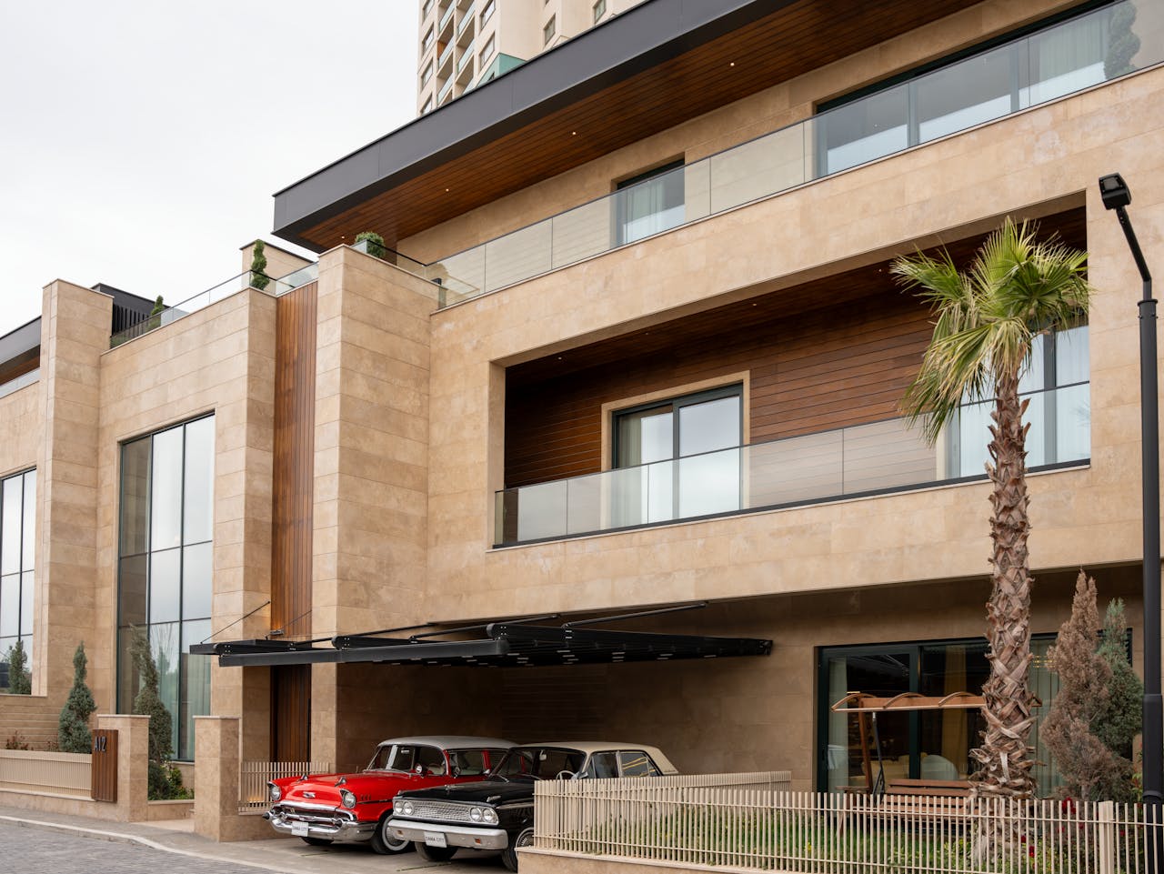 Exterior view of a modern luxury building with vintage cars parked under a sleek balcony.