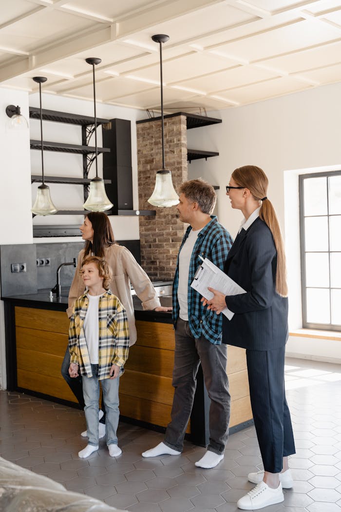 Family exploring a modern home kitchen with a real estate agent, showcasing buying opportunities.